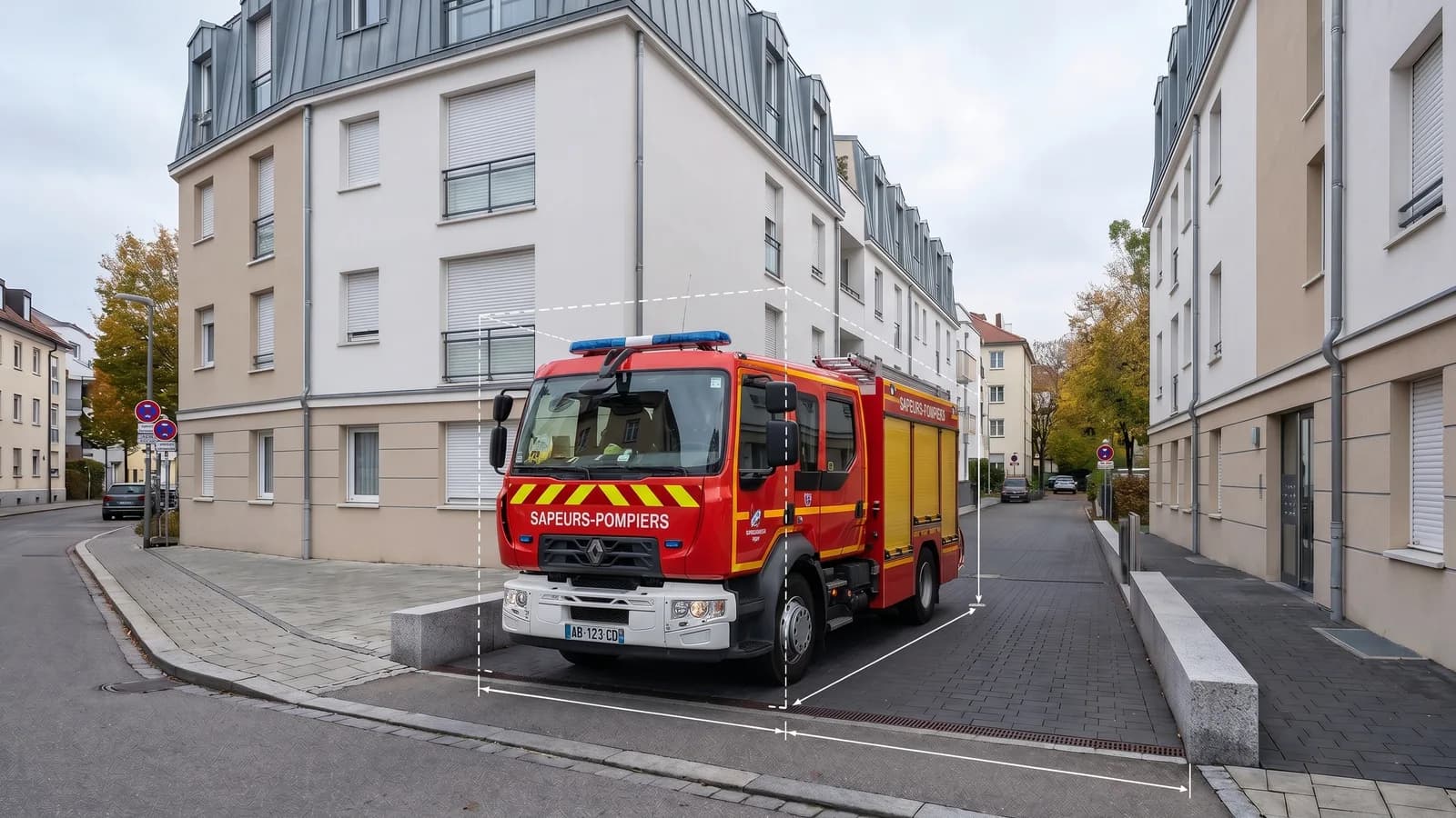 Engin d'incendie s'engageant dans une voie d'accès étroite entre des bâtiments d'habitation
